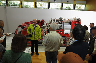 リチャード館長，後ろは津波で大破した消防車両